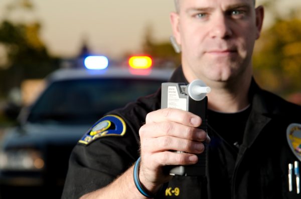 ABOGADO DEFENSOR DE DUI EN VISTA 2 Oficial de policía sosteniendo una máquina de alcoholemia