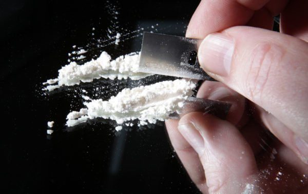 Una persona cortando cocaína con una cuchilla de afeitar.
